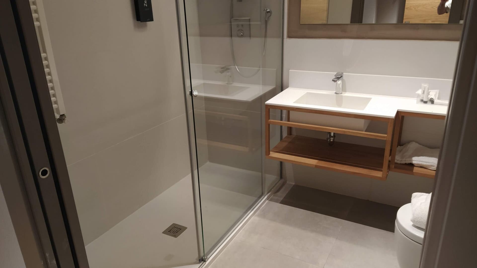 Baño después de la reforma con plato de ducha de obra y mampara de cristal